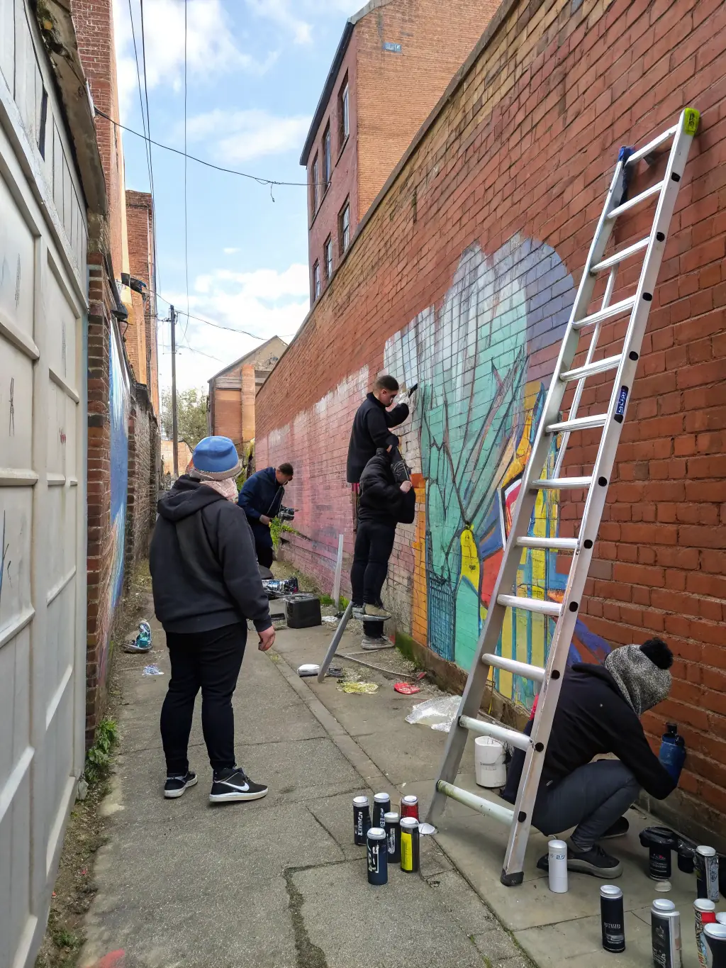 A dynamic image of a group of artists collaborating on a large-scale mural during a GOD'ART CREATION urban art project, highlighting community engagement and artistic expression.