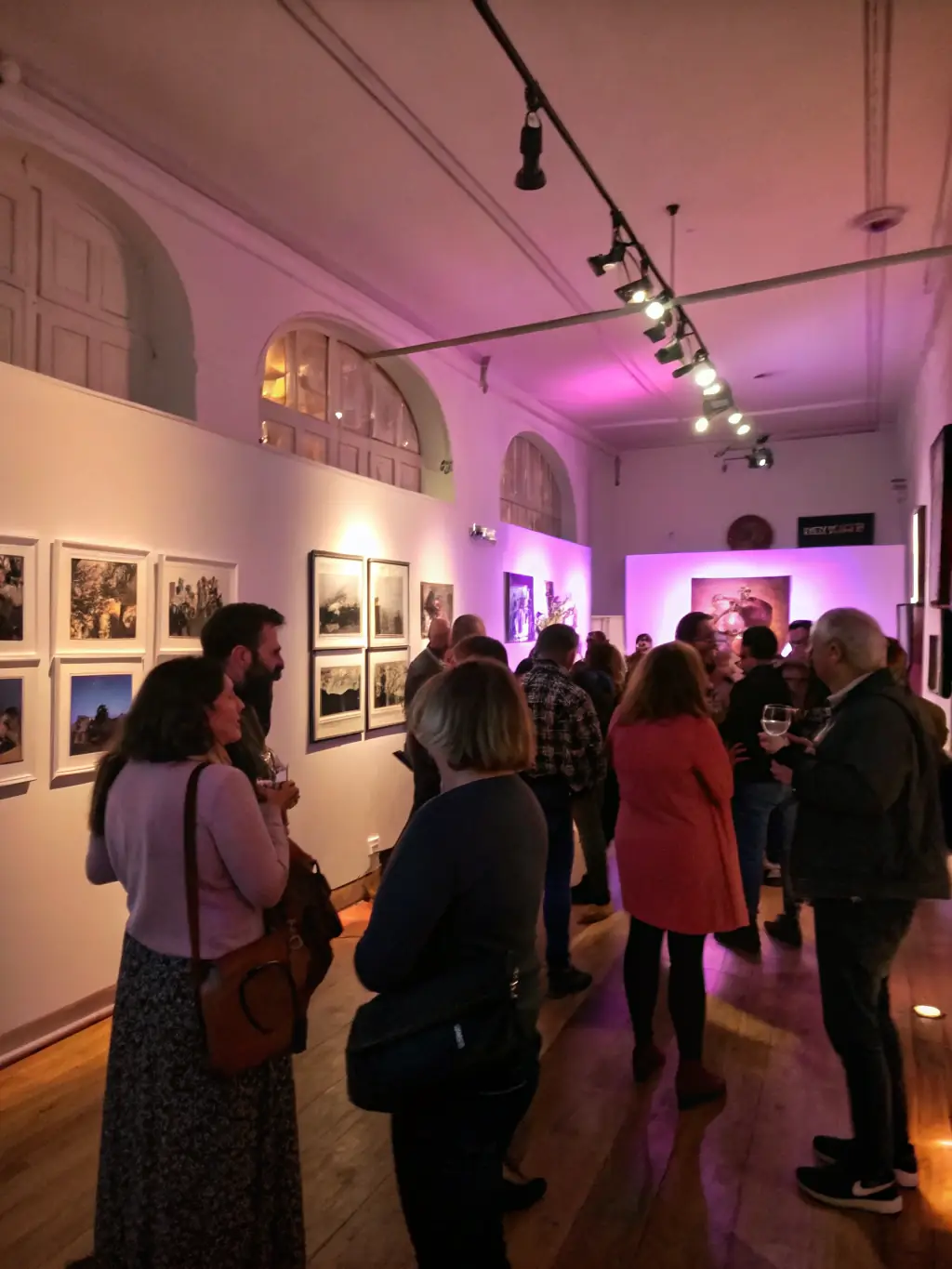 A photograph of an art exhibition opening night, featuring artists and attendees engaging with the displayed artwork, capturing the essence of GOD'ART CREATION's art showcases.
